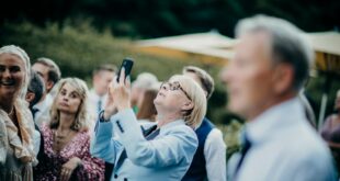 an elderly woman taking a photo with her phone