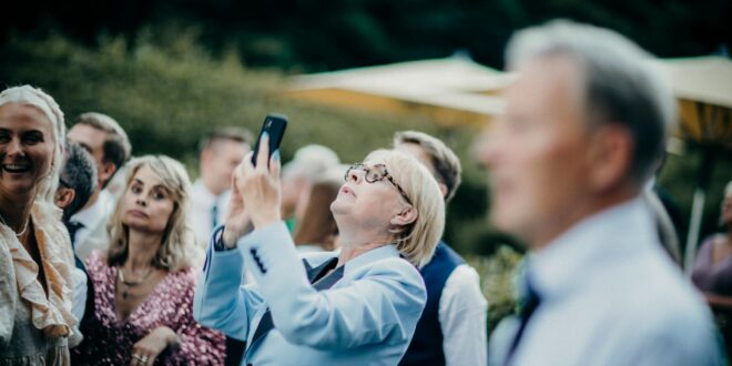 an elderly woman taking a photo with her phone