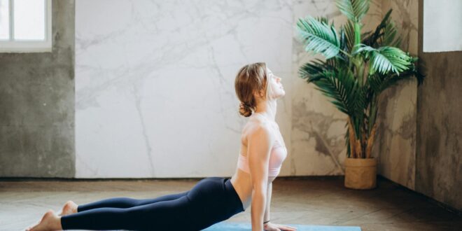 woman in pink sports bra and black leggings doing yoga on yoga mat