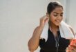 woman in sports clothing putting earphones in and smiling