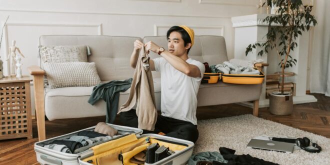 a man packing clothes in a suitcase